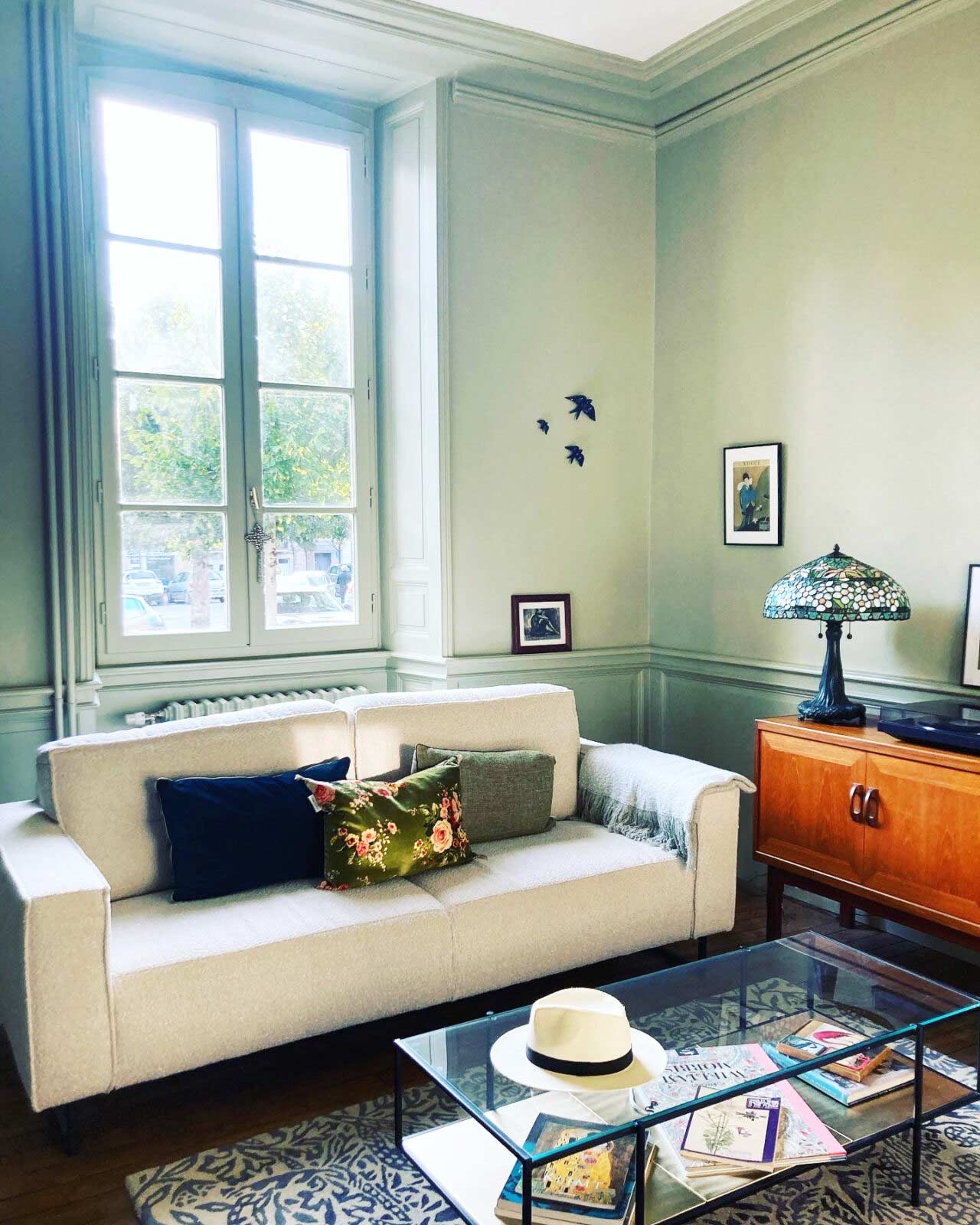 View of the room, with a sofa and a window letting in natural light to the room.