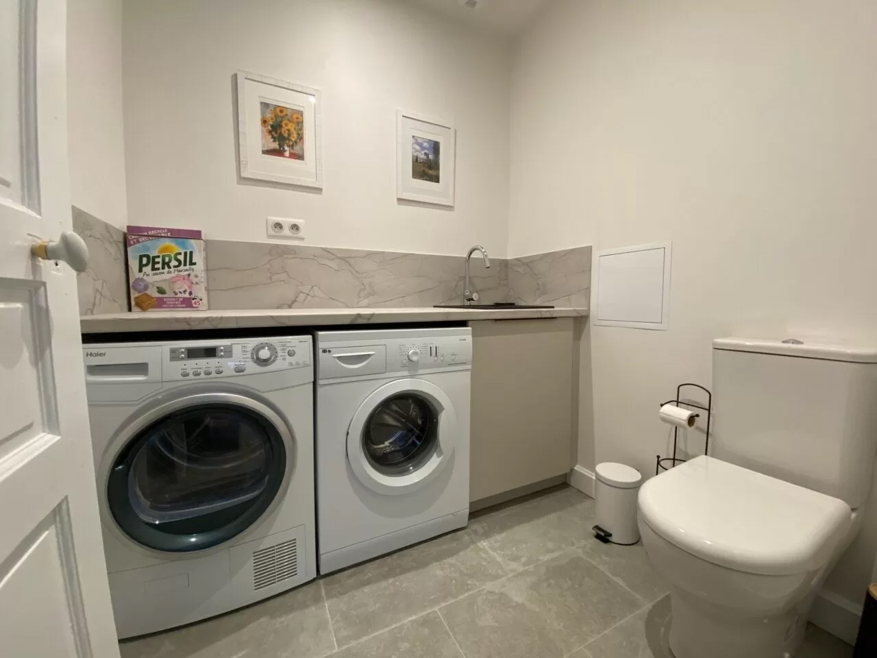 View of laundry room, washing machine and dryer including a toiler and sink for guest.